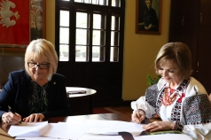 Dwie kobiety podpisują w gabinecie porozumienie.