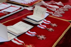 Na zdjęciu na czerwonym materiale odznaki PCK oraz książeczki