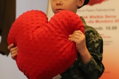 Chłopiec trzyma poduszkę w kształcie serca.