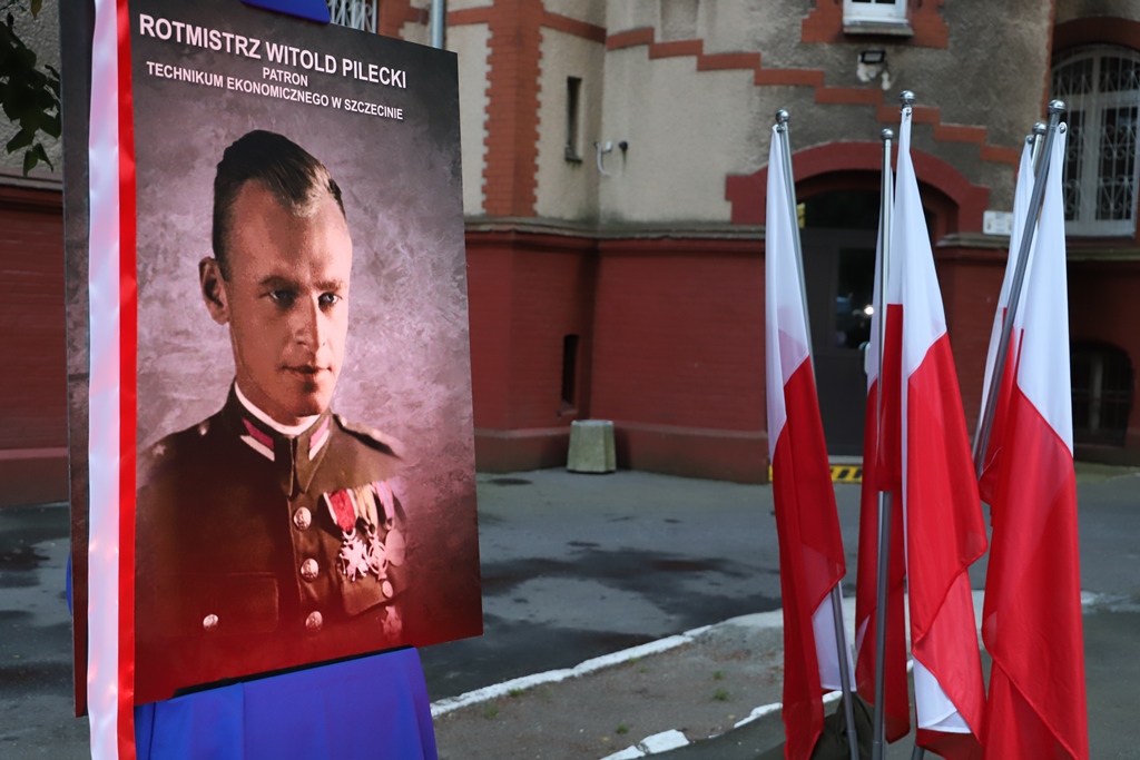 Po lewej stronie portret mężczyzny w mundurze. Po prawej flagi biało-czerwone.