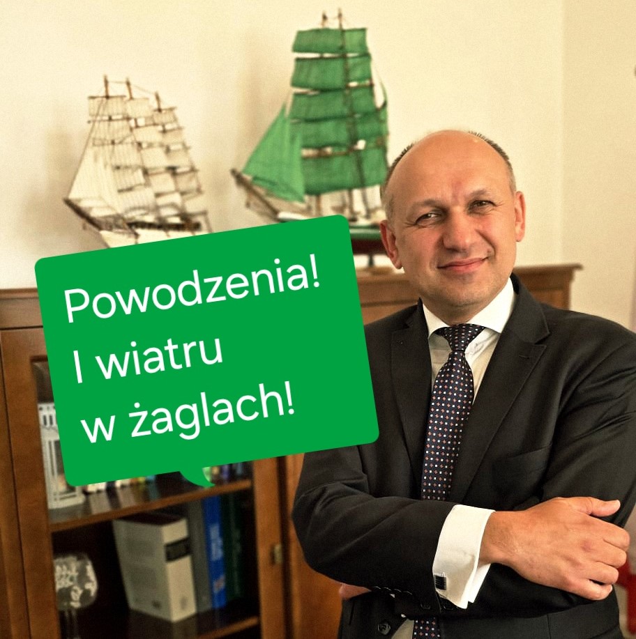 Zachodniopomorski Kurator Oświaty Paweł Palczyński uśmiechnięty, obok dymek z tekstem: Powodzenia! I wiatru w żaglach! za nim dwa modele żaglowców.